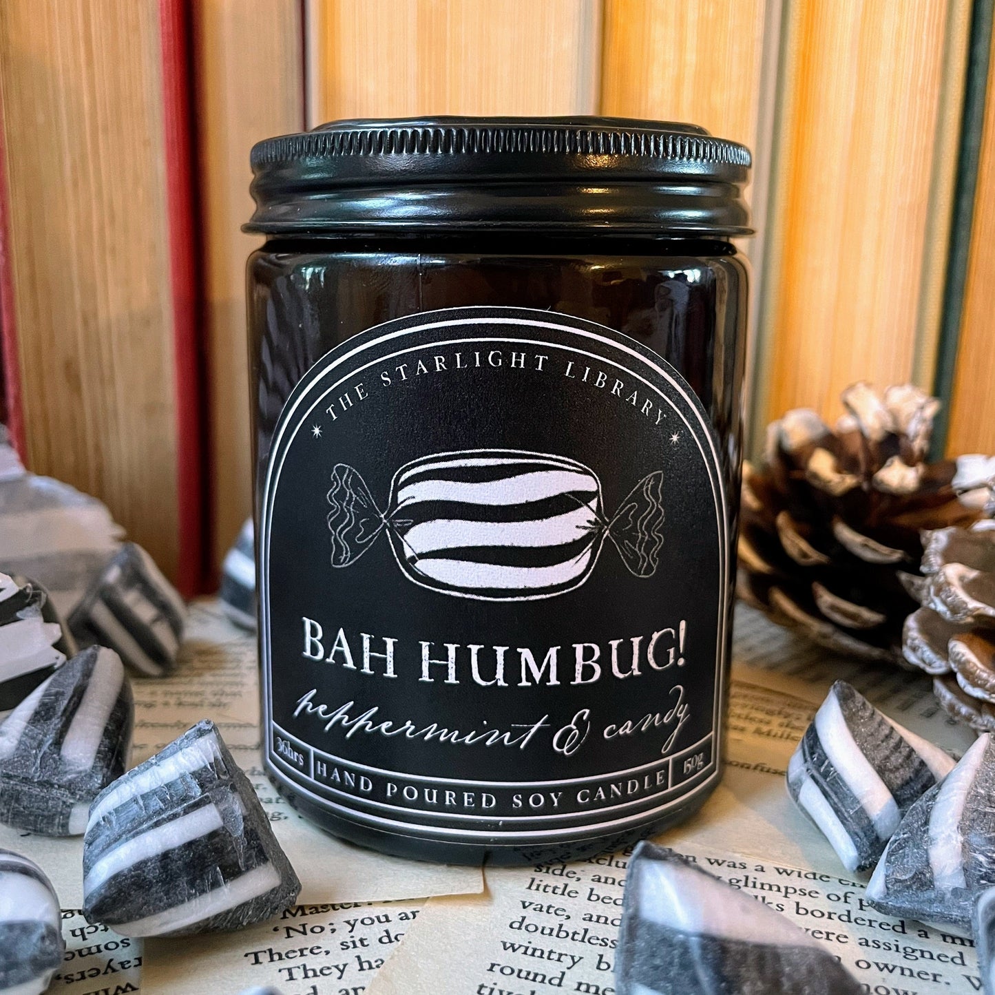 Black candle jar with 'Bah Humbug!' label on a surface with decorative elements