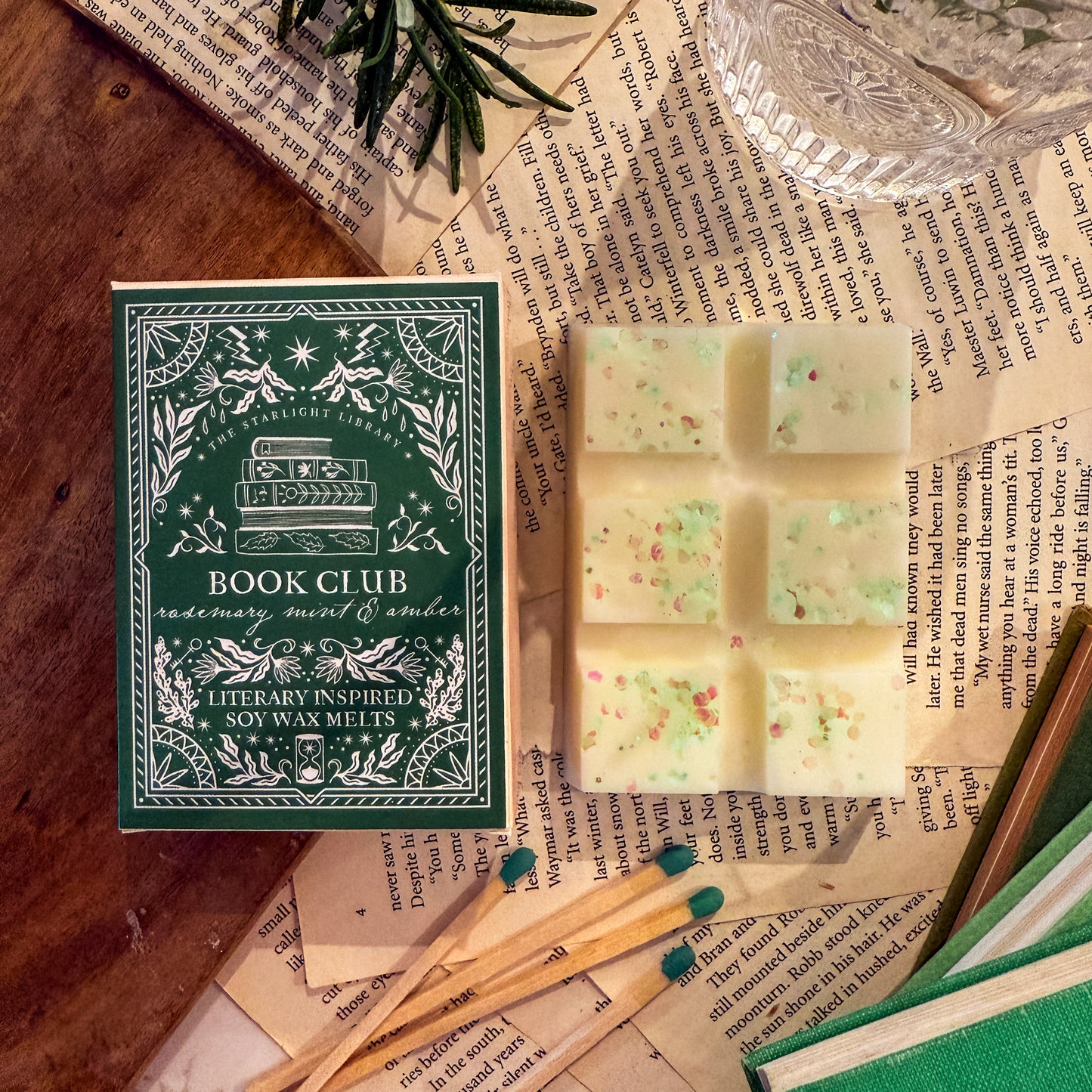 Book Club soy wax melts with packaging on a wooden surface with books and greenery.