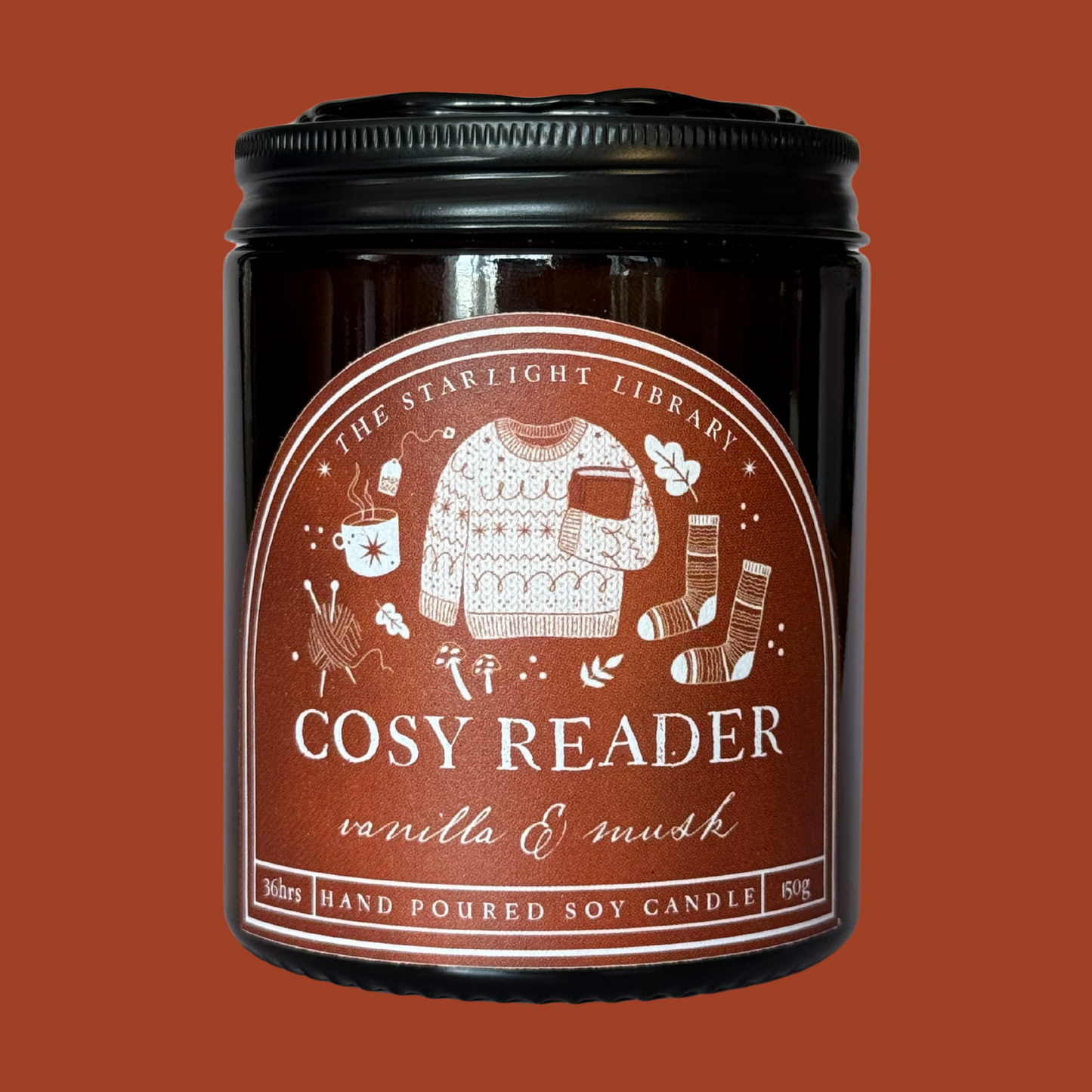 A Cosy Reader candle agaisnt a matching deep orange background.