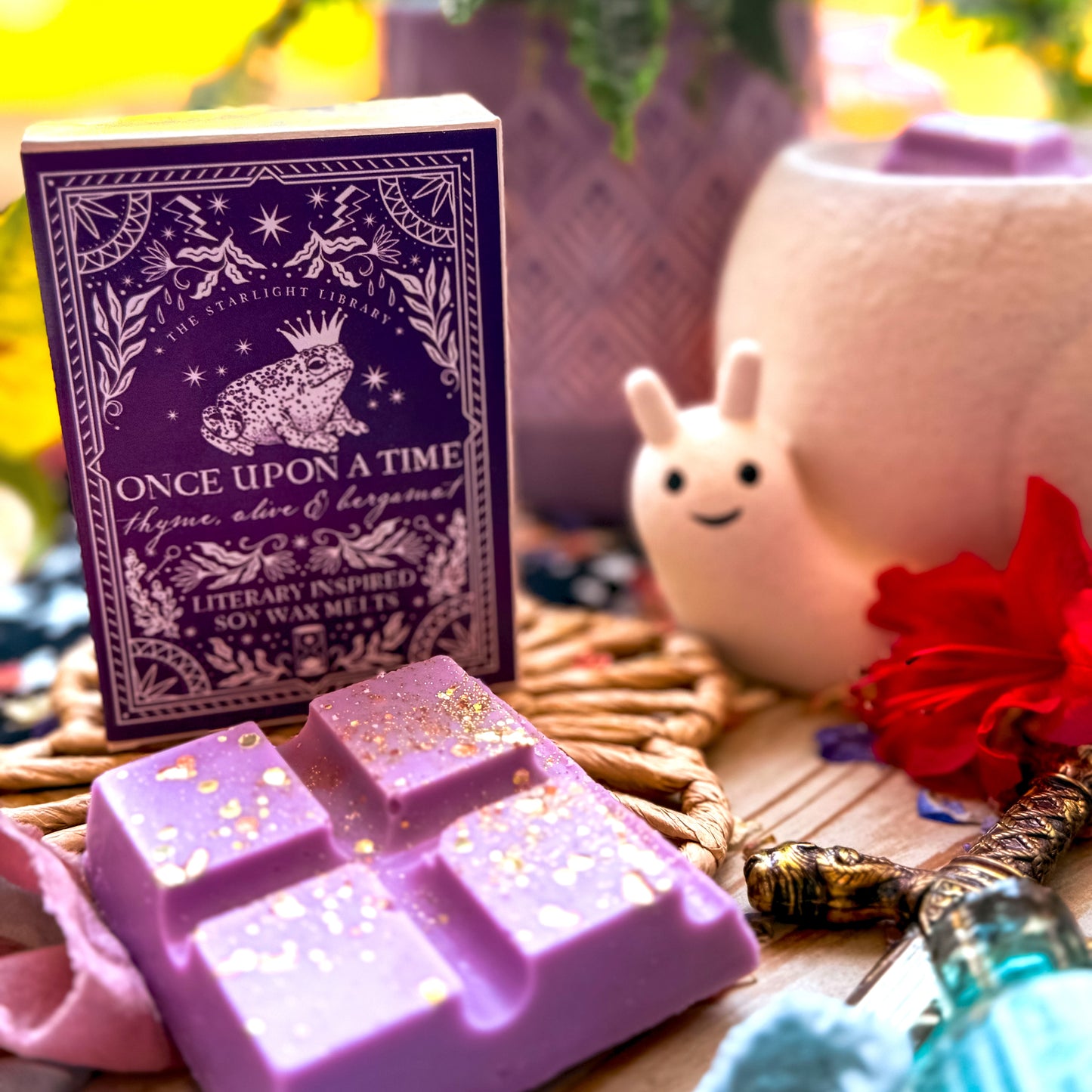 Once Upon A Time Literary Wax Melts with a broken up wax melt bar alongside and a smiley snail melter in the background