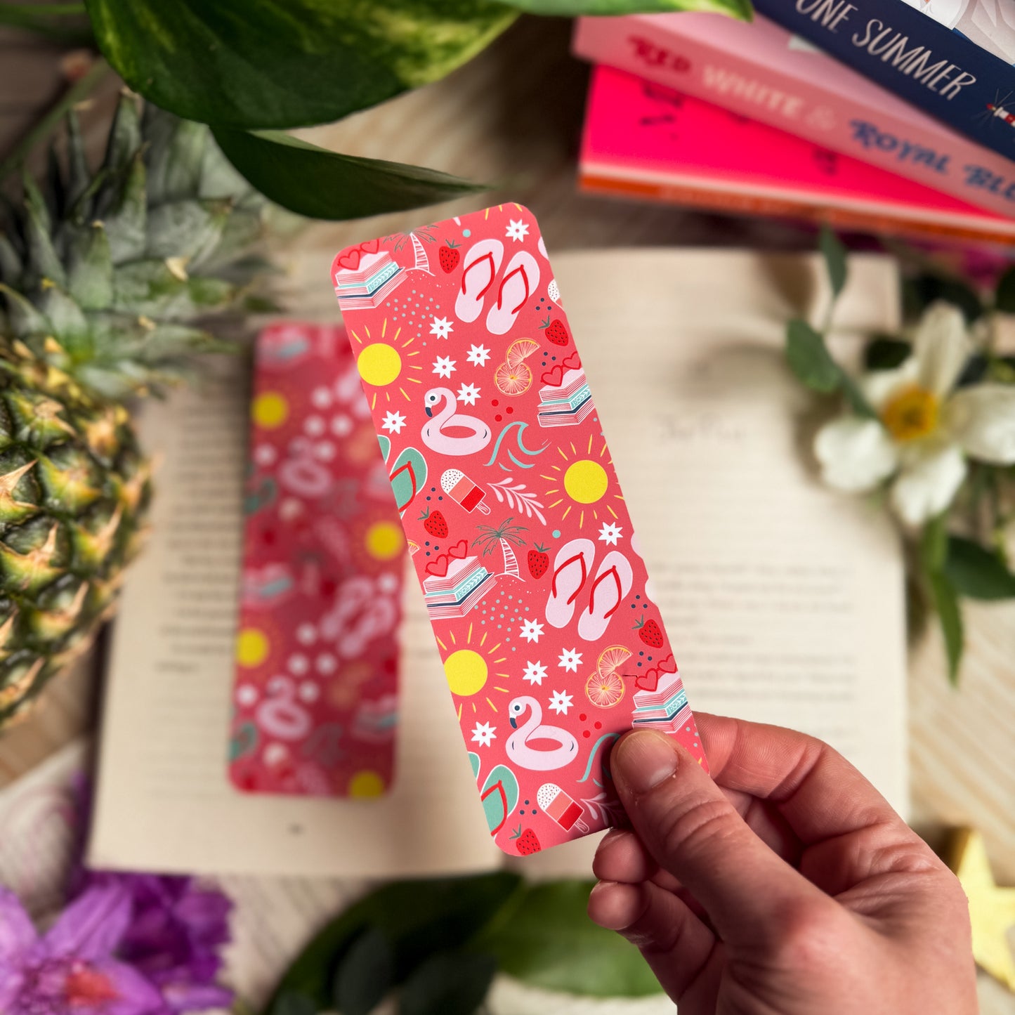 A Paperback Paradise bookmark, against a background of an open book, topical fruits and flowers.