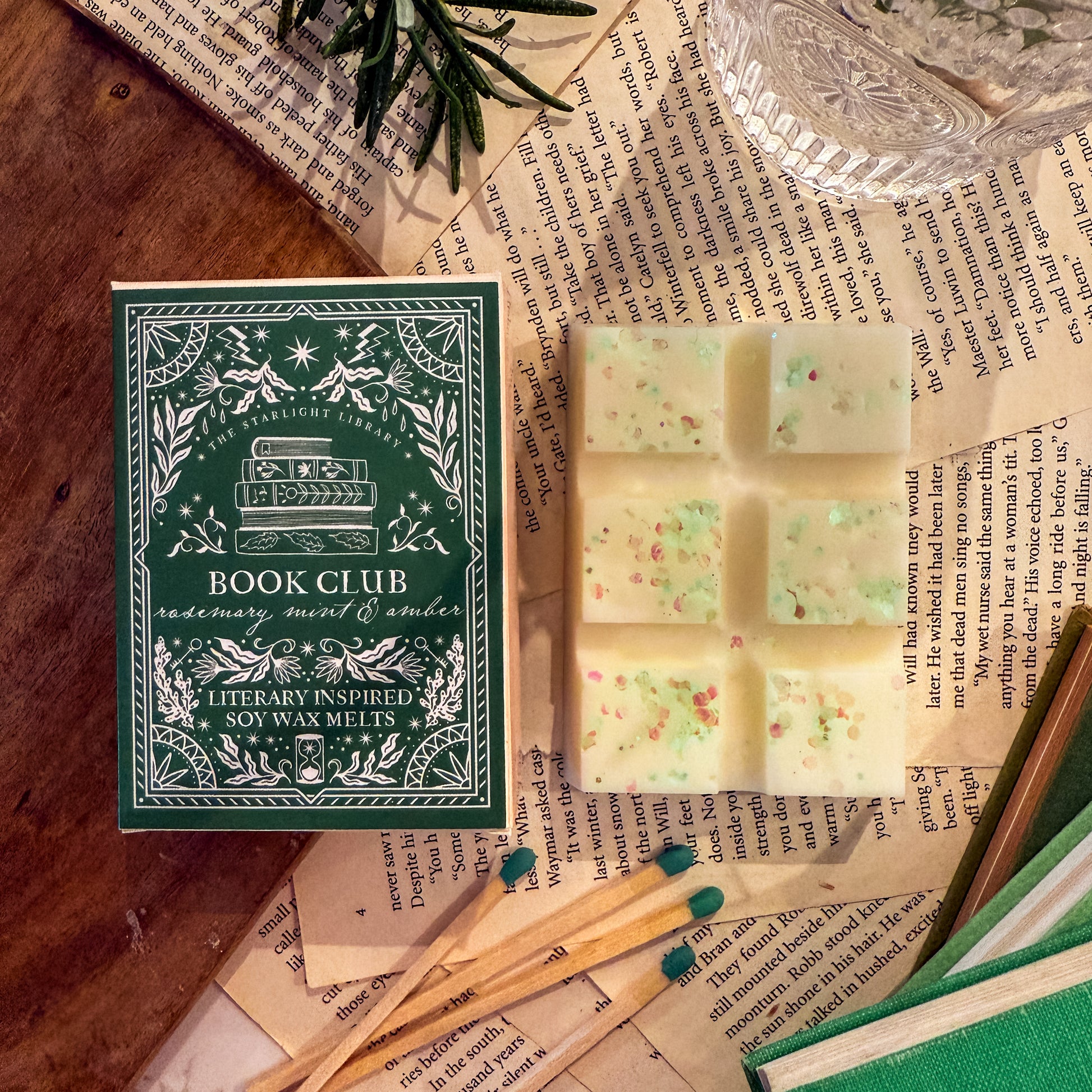 Book Club soy wax melts with packaging on a wooden surface with books and greenery.