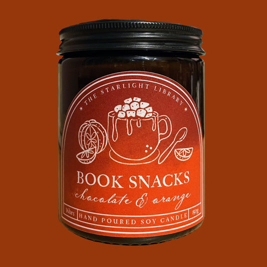 Jar of 'Book Snacks' chocolate & orange candle with a red label on an orange background