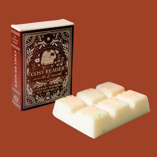 A Cosy Reader wax melt bar with it's book box against a warm orangey studio background.