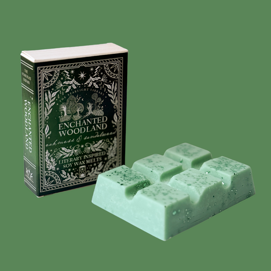 An Enchanted Woodland wax melt bar, with it's book box against a green studio background.