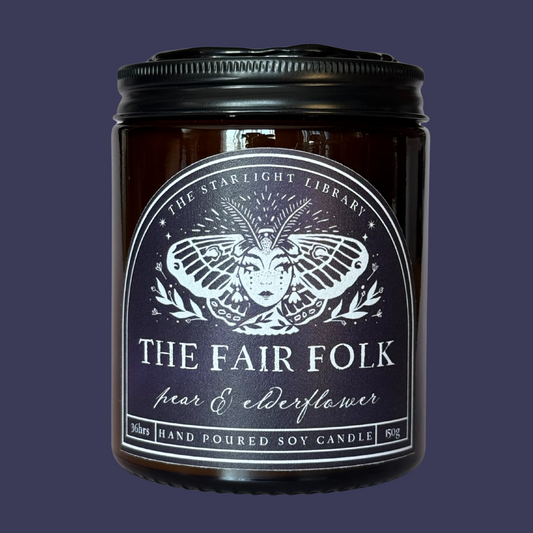 A Fair Folk candle against a matching dark blue studio background