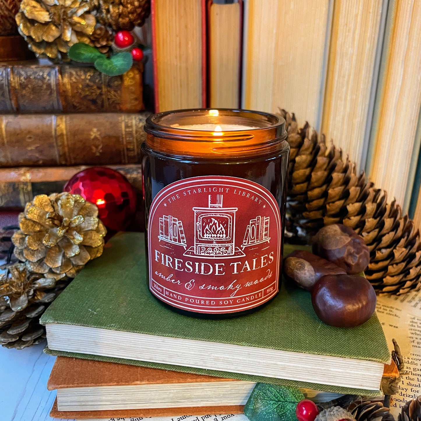 Candle labeled 'Fireside Tales' on a stack of books with decorative items.
