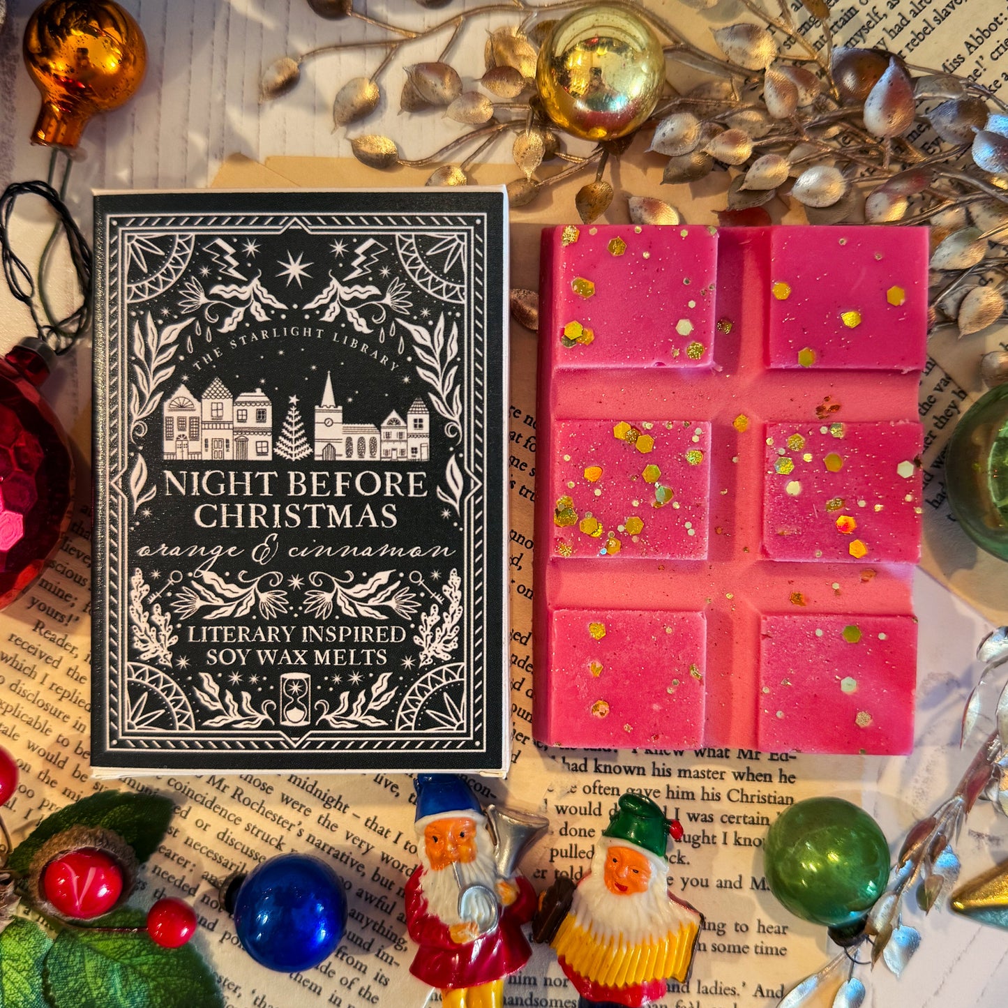 Decorative wax melts with a 'Night Before Christmas' book and small Santa figurines on an open book.