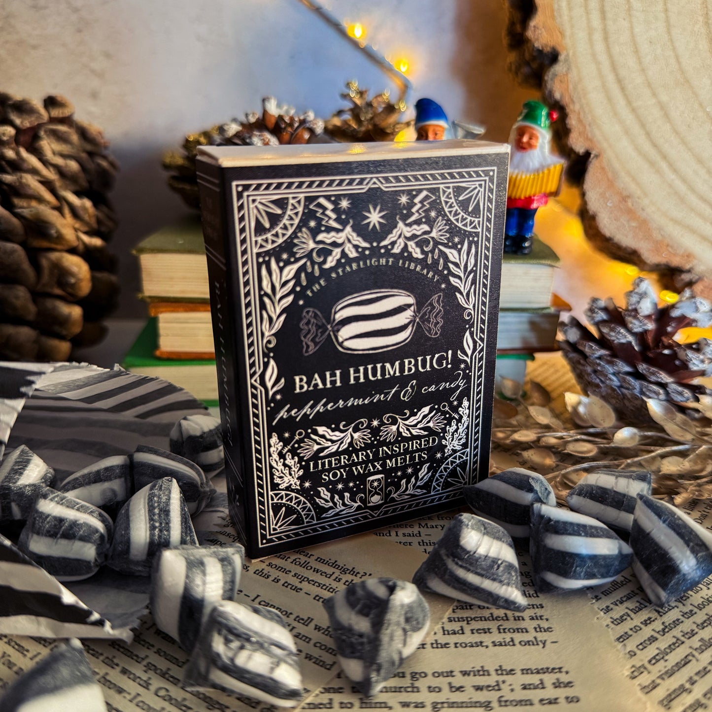 Decorative book with 'Bah Humbug' text on a surface with small figurines and string lights.