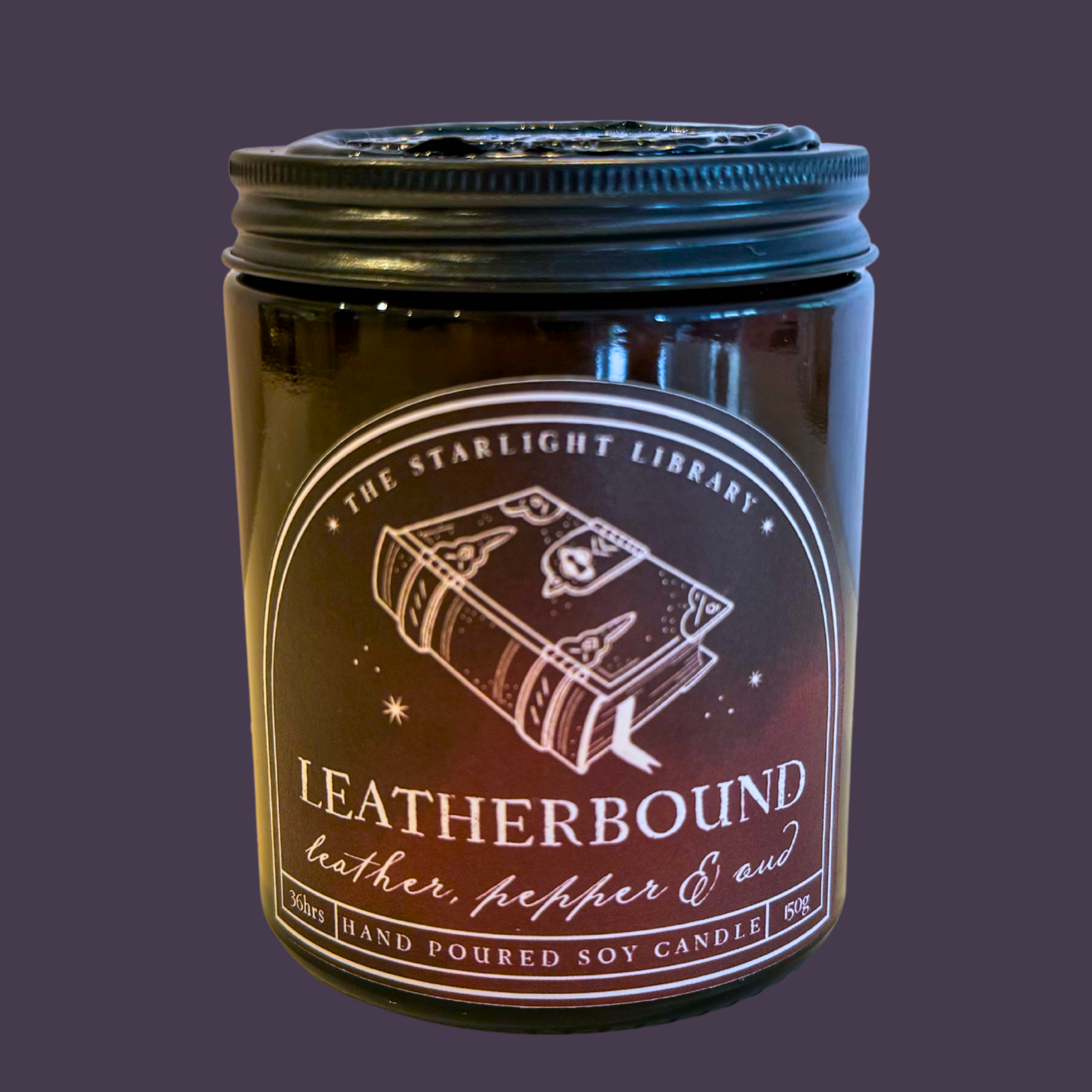 A Leatherbound candle against a dark purple studio background.
