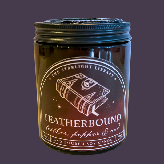 A Leatherbound candle against a dark purple studio background.