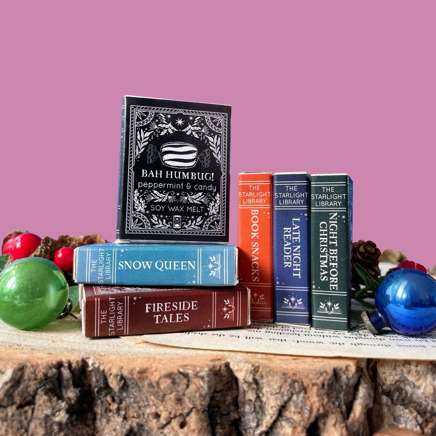 Stack of mini melt books on a wooden surface with a pink background