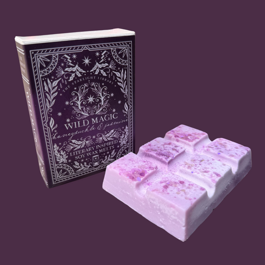 A Wild Magic wax melt , with it's book box, in front of a purple studio background.